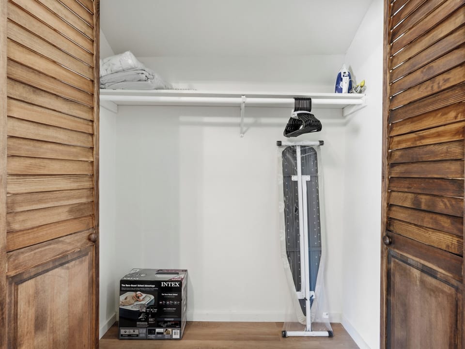 Spacious closet with hangers, linens, iron, and extra storage