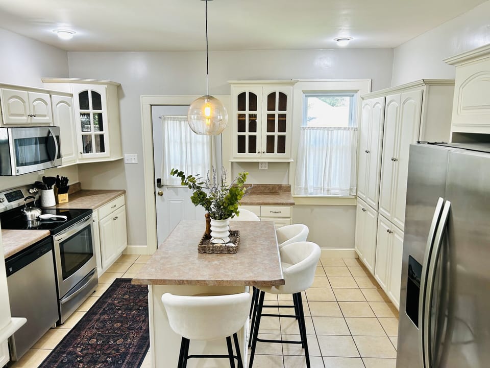 Bright full kitchen with island seating and stainless steel appliances
