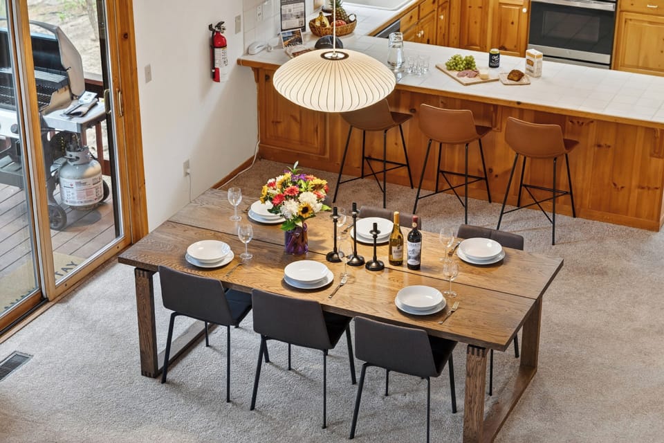 Overhead view of the dining setup highlighting the rustic-modern table, ample seating for six, and close proximity to the kitchen breakfast bar.