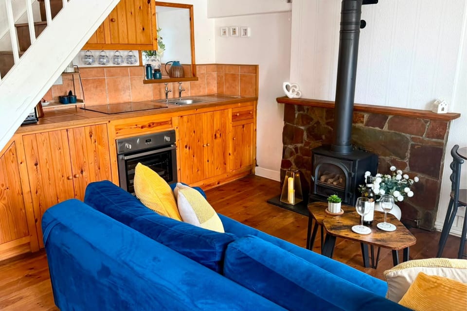 Open-plan living space with kitchen, sofa and cosy wood burner