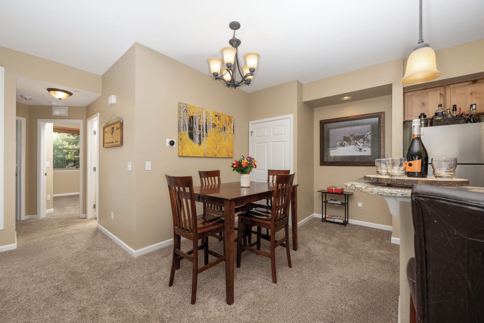 Your inviting dining space awaits with elegant lighting, warm wood furnishings, and thoughtful touches like fresh flowers and wine—perfect for memorable meals together.