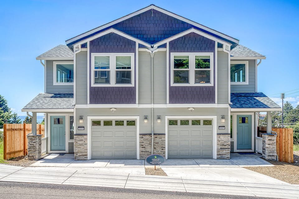 Modern two-unit duplex featuring blue and gray exterior with two-car garages and private entrances for each residence.