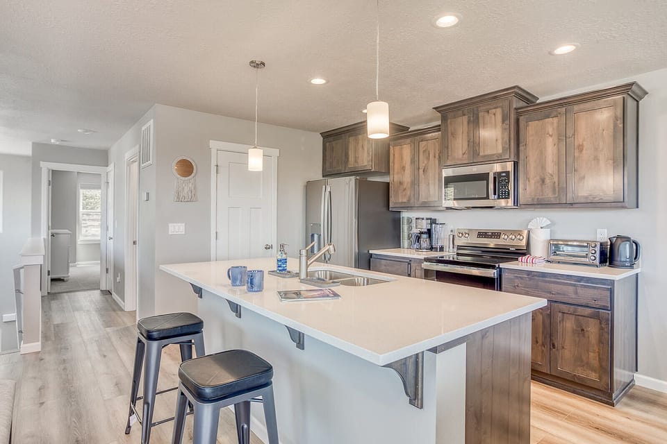 Your fully equipped kitchen awaits, complete with sleek stainless steel appliances, warm wood cabinetry, and a spacious island perfect for morning coffee or meal prep.