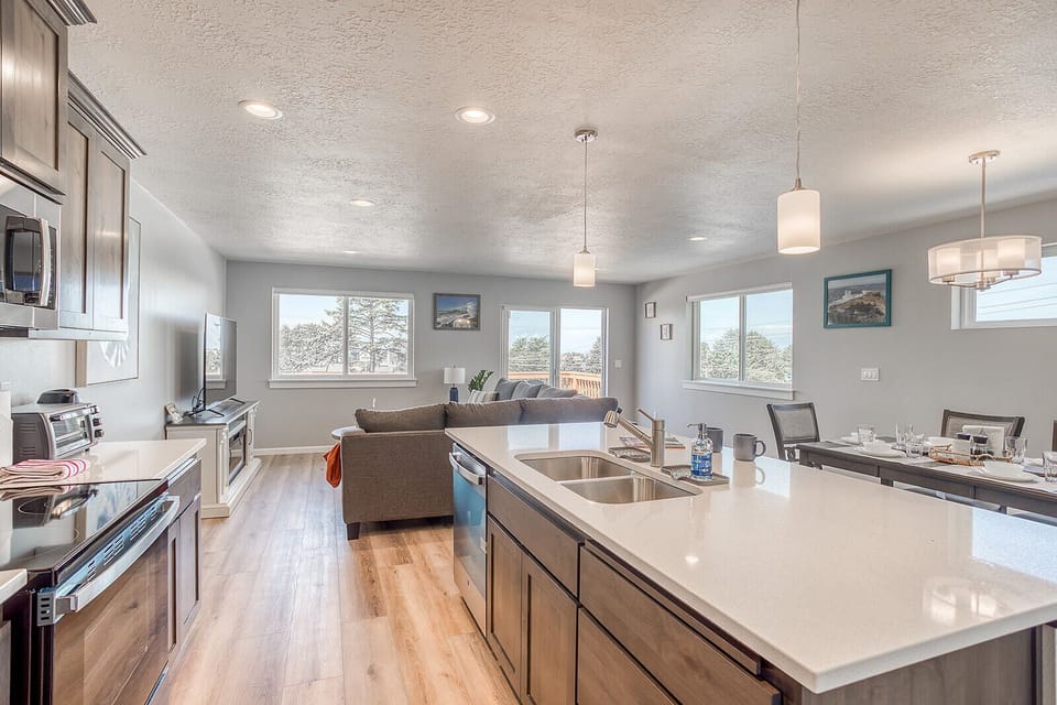 Gather around this bright, open kitchen with gleaming countertops, stainless appliances, and mountain views streaming through every window—your perfect home base for meals and memories.