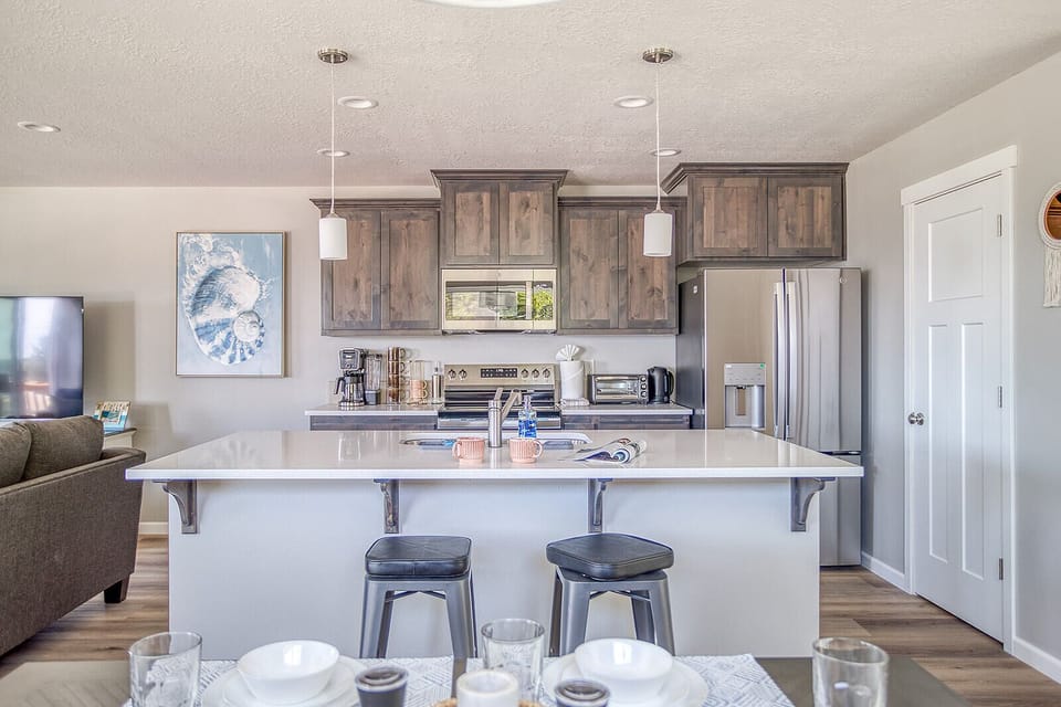 Gather around this spacious kitchen island where you'll enjoy morning coffee and meal prep together, surrounded by warm wood cabinetry and modern stainless appliances that make cooking effortless.