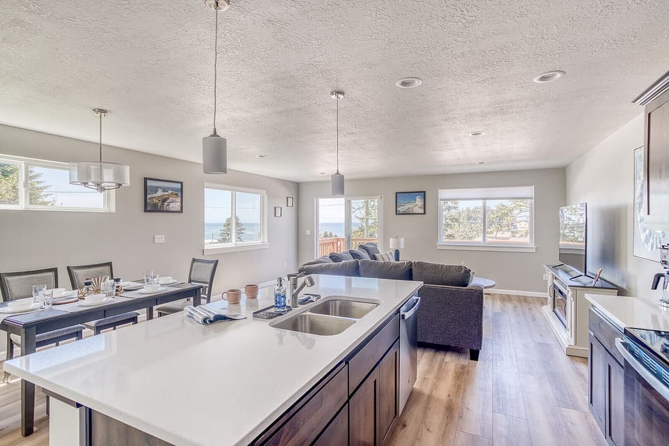 You'll love the open layout where your kitchen flows into the dining and living areas—perfect for gathering with everyone while cooking. Those windows frame beautiful water and mountain views, flooding the space with natural light.