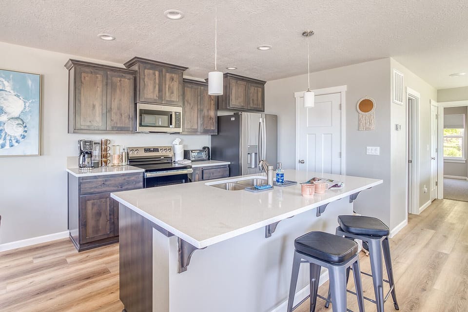 Gather at the spacious island in this modern kitchen, featuring stainless appliances, rich wood cabinetry, and gleaming countertops perfect for cooking and entertaining together.