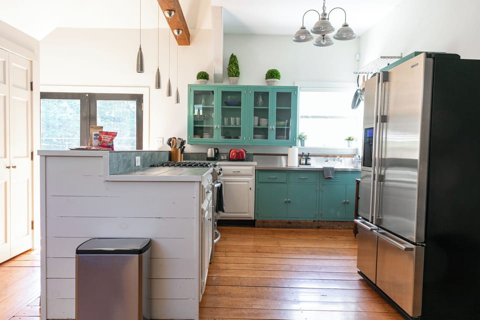 Full kitchen with stainless steel fridge, gas stove & teal cabinets