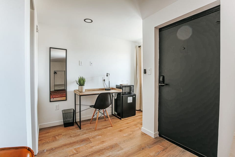 Settle into your cozy workspace with a stylish desk, mini fridge, and modern chair—all bathed in natural light.