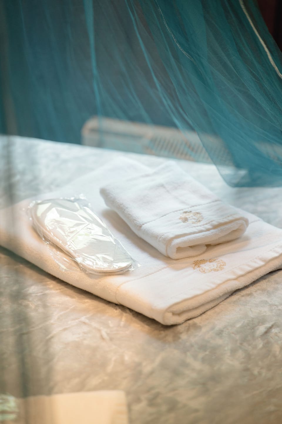 Fresh towels and sleep mask on a cozy, canopy-draped bed