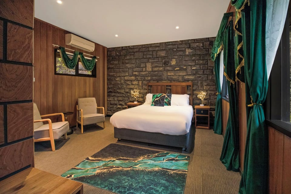 Stylish bedroom with stone accent wall, plush bed, and elegant emerald accents