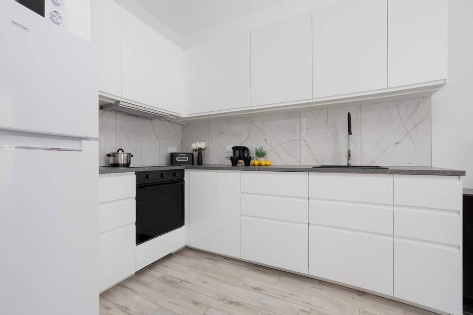 Modern kitchenette with sleek white cabinetry and integrated appliances.