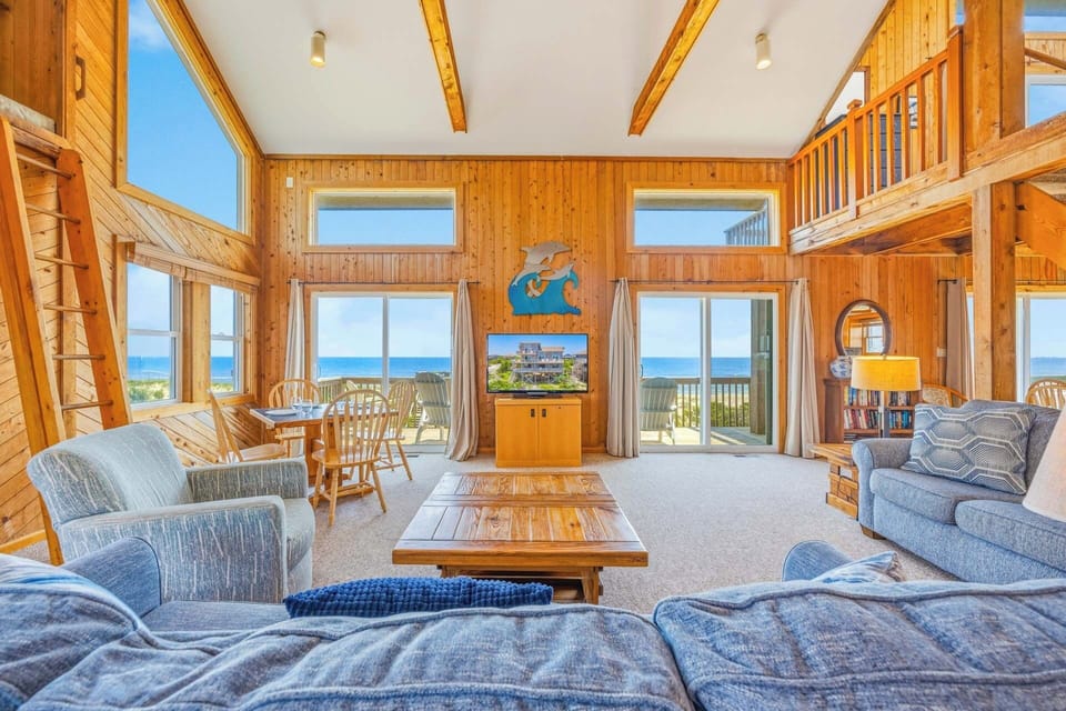 Step into your sunlit retreat, where soaring ceilings and panoramic ocean views frame every moment. Sink into plush seating, gather around the rustic coffee table, and let the coastal breeze drift through open doors—your perfect escape awaits.