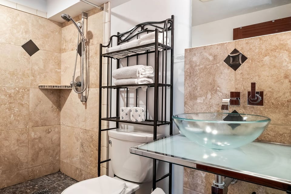 Step into your private spa-like retreat with walk-in shower, elegant glass vessel sink, and plush towels ready for your refreshing morning routine.