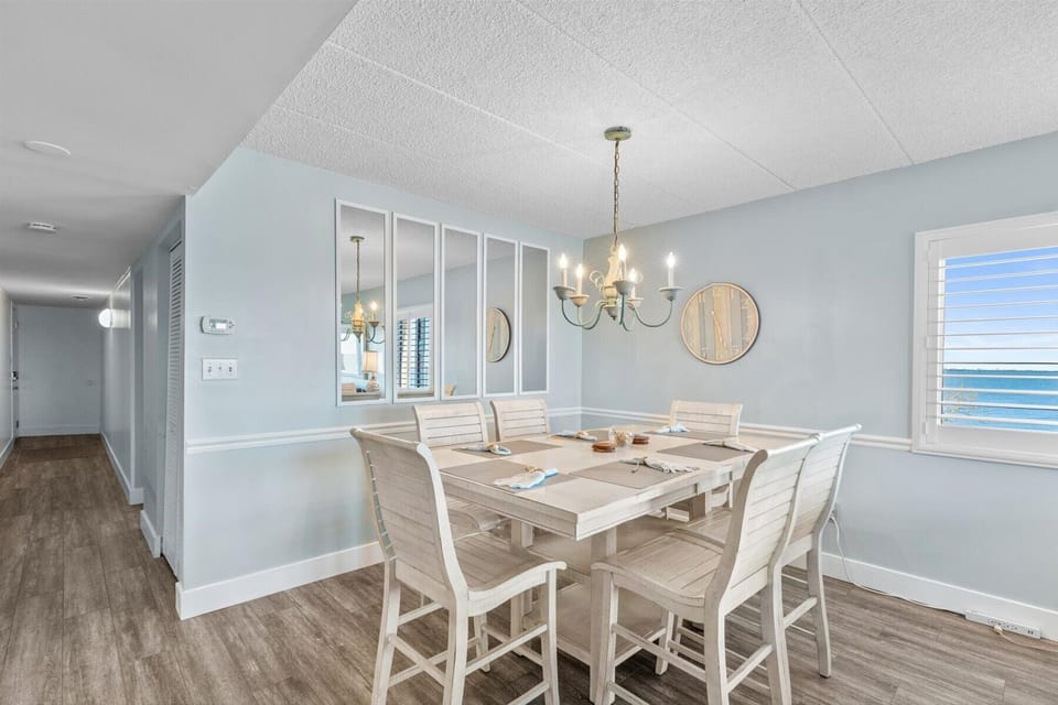 A crisp, bright angle of the dining area showcasing the ample space and coastal design elements of the unit.