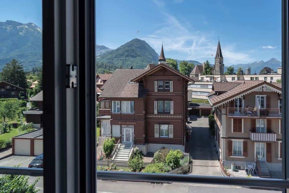 View from the apartment window over traditional Swiss buildings and the mountain landscape.