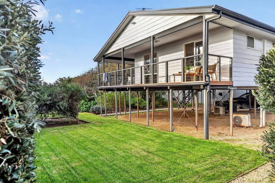 Elevated above the gardens, the exterior captures the relaxed character of a classic coastal escape with generous outdoor living spaces.