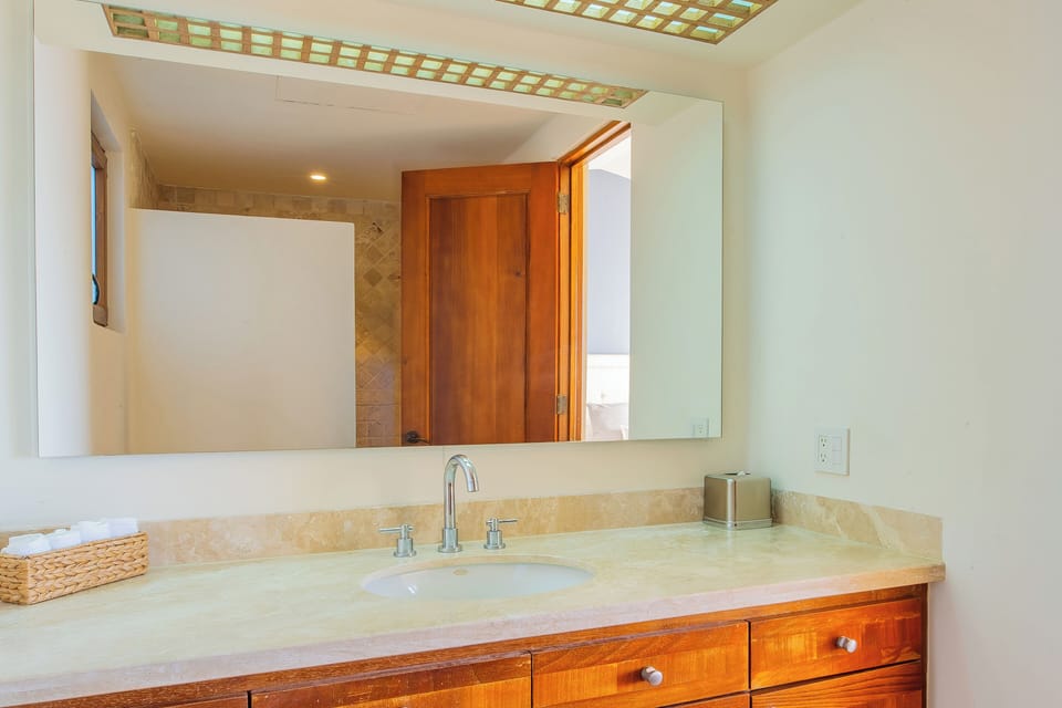Bathroom 5 · Fresh towels await you in this bright bathroom with warm wood cabinetry, polished stone counters, and a skylight that fills the space with natural light.