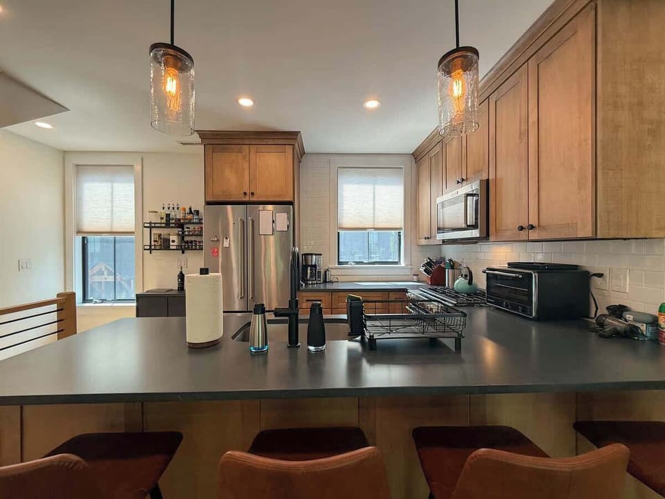 A wider view of the kitchen shows the full layout, with the dark countertops, stainless appliances, and peninsula seating all working together in an open, well-lit space.