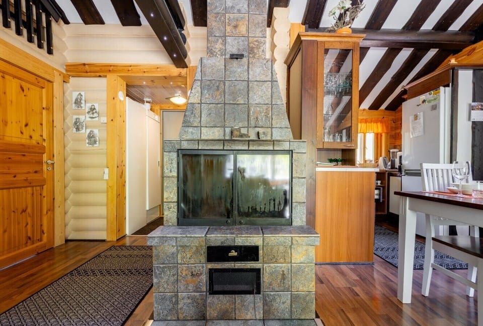 The living area`s stone fireplace surround adds rustic charm beneath the striking wood-beamed ceiling.