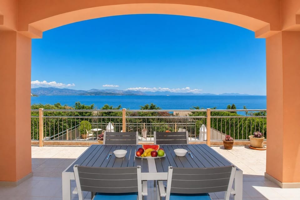 Covered terrace dining area with panoramic sea views and a bright Mediterranean setting.