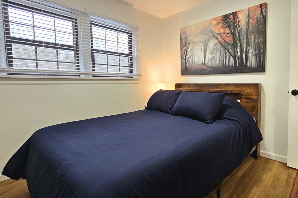 Bright, cozy bedroom with queen bed, wood floors & serene art.