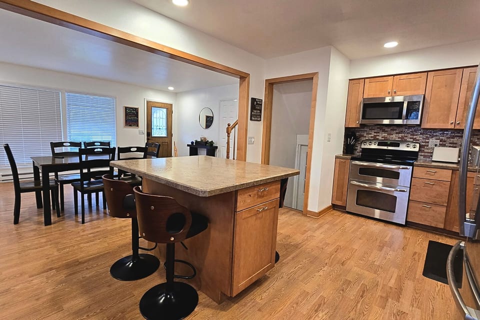 Open kitchen with island, stainless appliances, and dining for six.