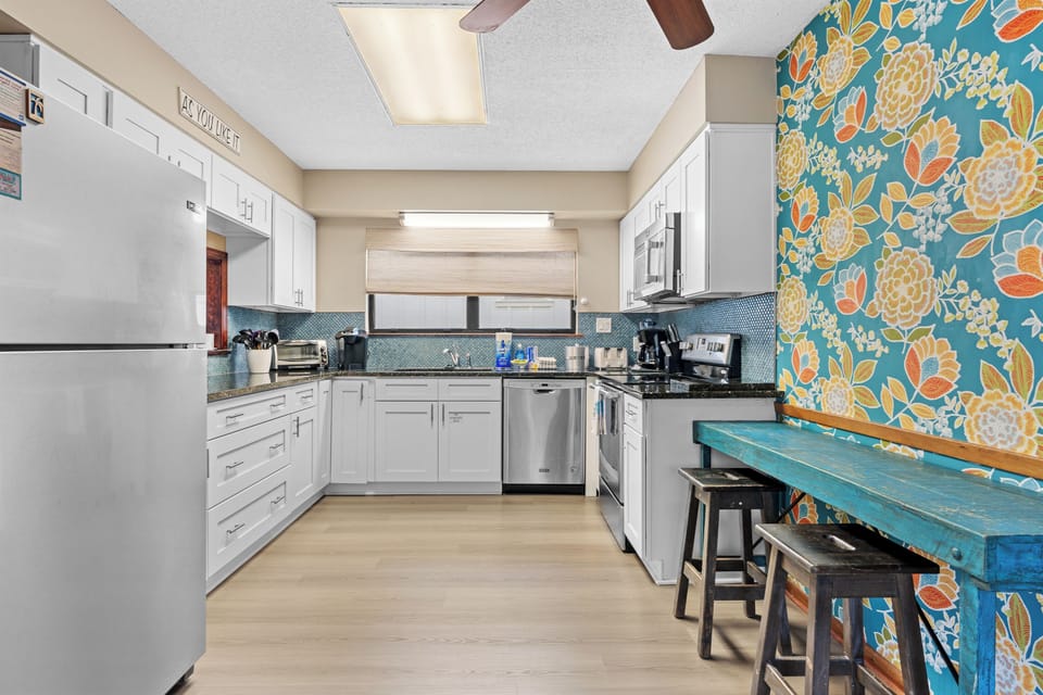 Kitchen with modern white cabinetry contrasted with a vibrant botanical backsplash.