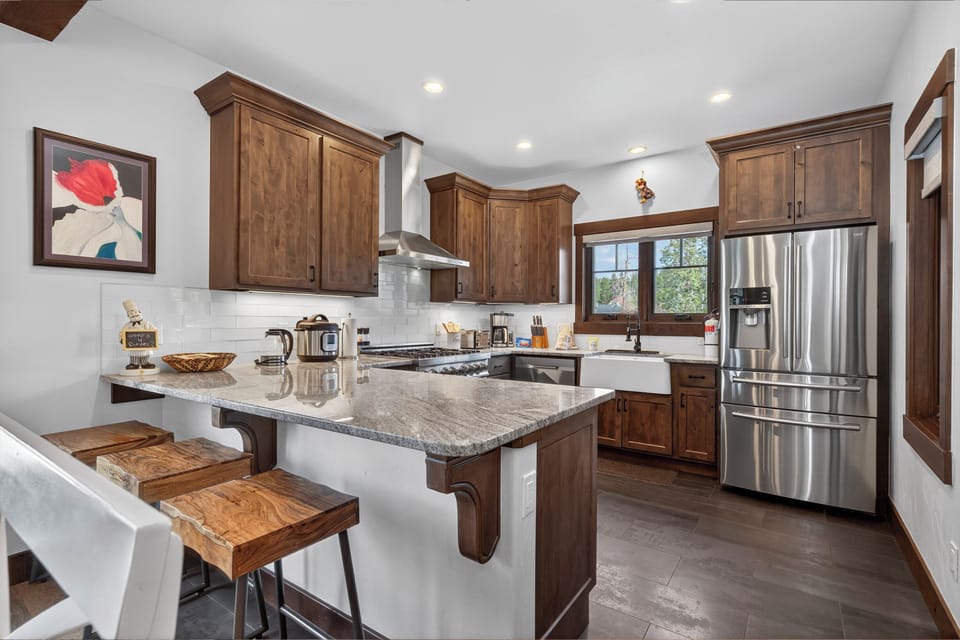 Your gourmet kitchen awaits with gleaming granite counters, rich wood cabinetry, and top-tier appliances—perfect for morning coffee or preparing vacation feasts together.