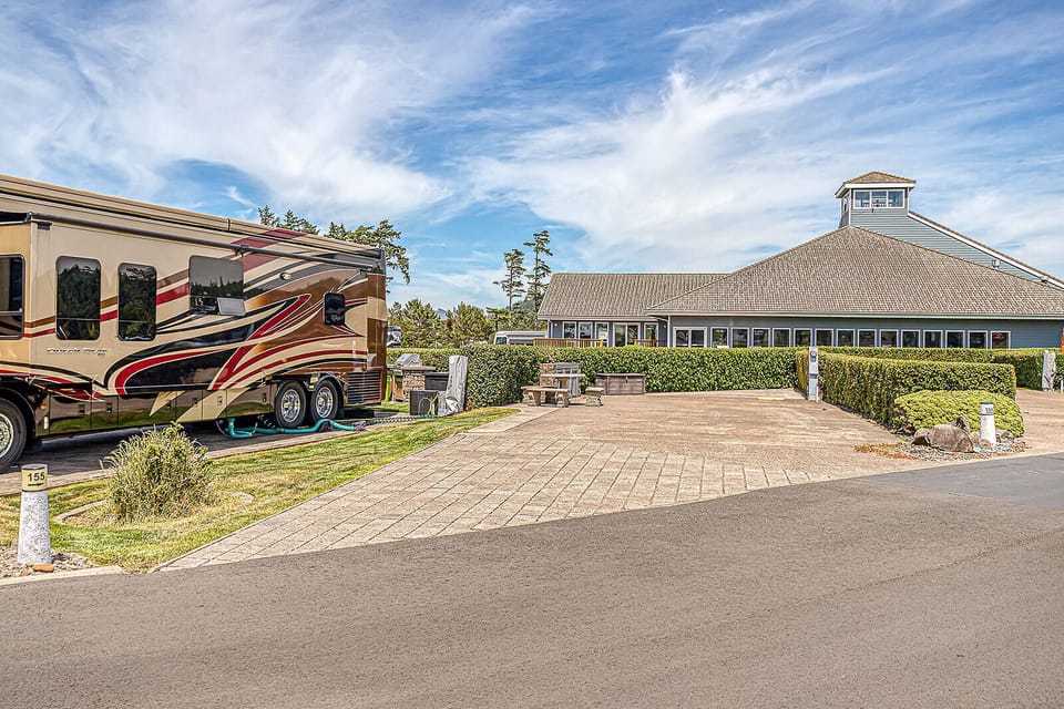 Property exterior features well-maintained landscaping, paved parking areas, and a distinctive octagonal building with wrap-around windows offering scenic views under open skies.