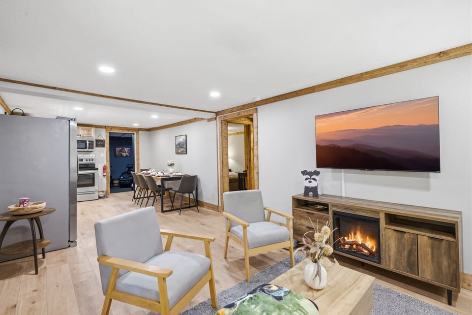 Cozy open living space with fireplace, TV, dining area, and full kitchen