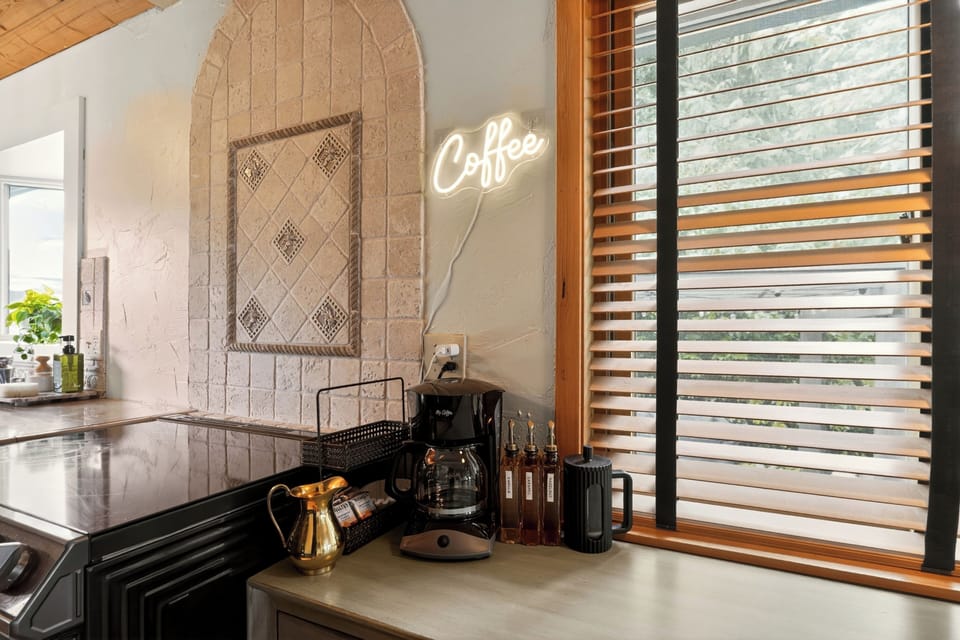 Cozy coffee bar with neon sign, syrups, and warm natural light