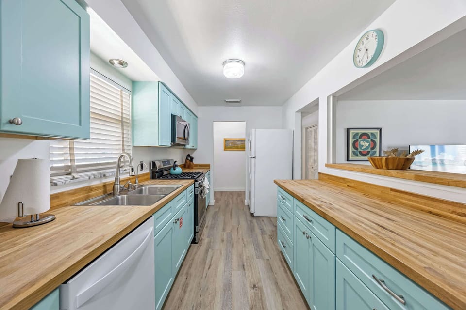 Bright kitchen with turquoise cabinets and wooden countertops for a fresh, modern feel.