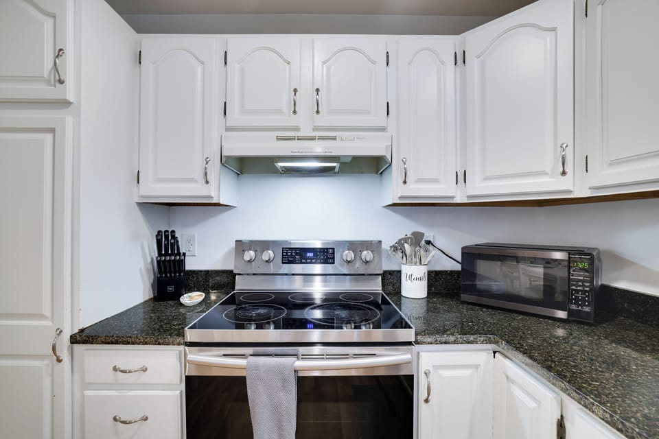 Bright and fully stocked kitchen with granite counters and stainless steel stove