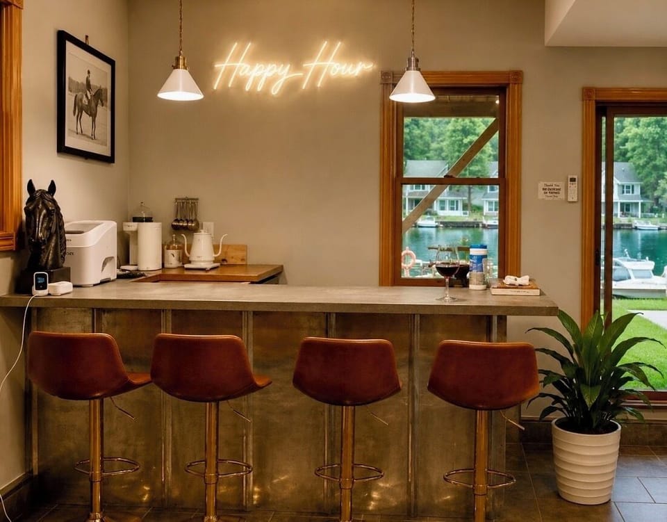Gather around the custom bar with warm neon ambiance, waterfront views, and the perfect spot for cocktails, coffee, or evening conversation.