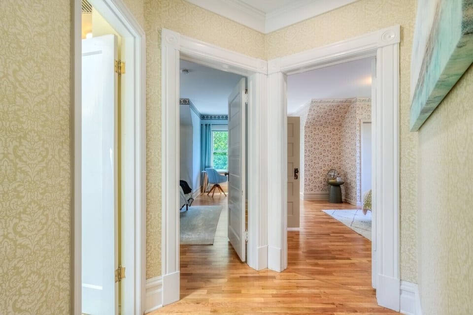 The upstairs landing connects two bedrooms and the shared bathroom, featuring original hardwood floors and historic charm.