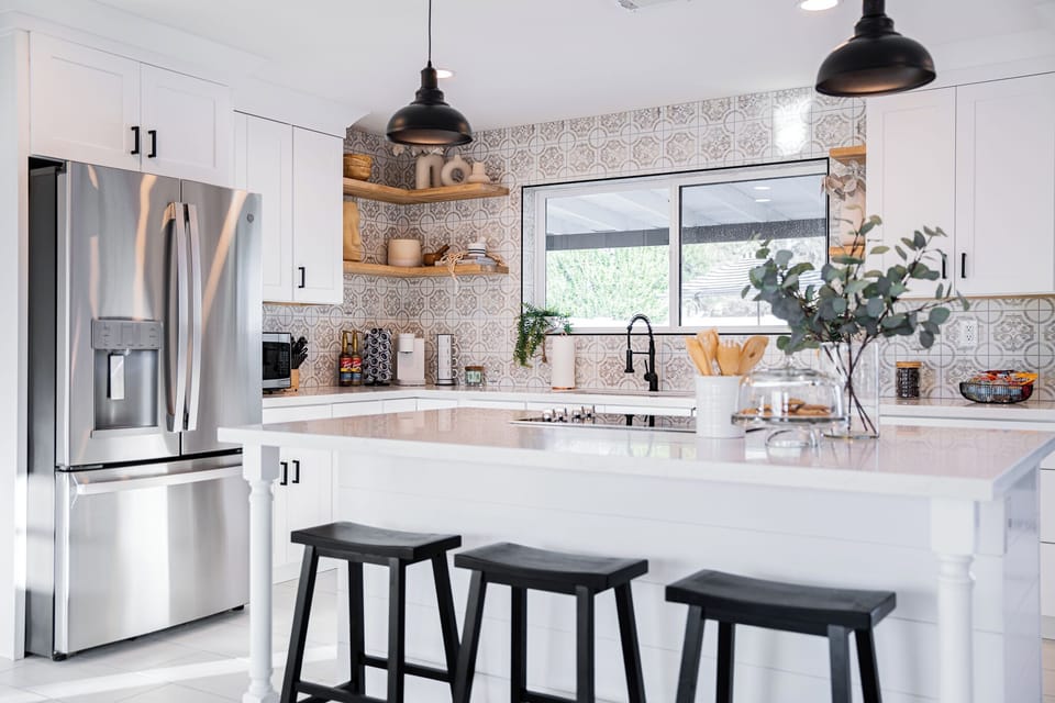 Gourmet kitchen prep zone featuring premium stainless steel appliances and wide windows looking out to the property.