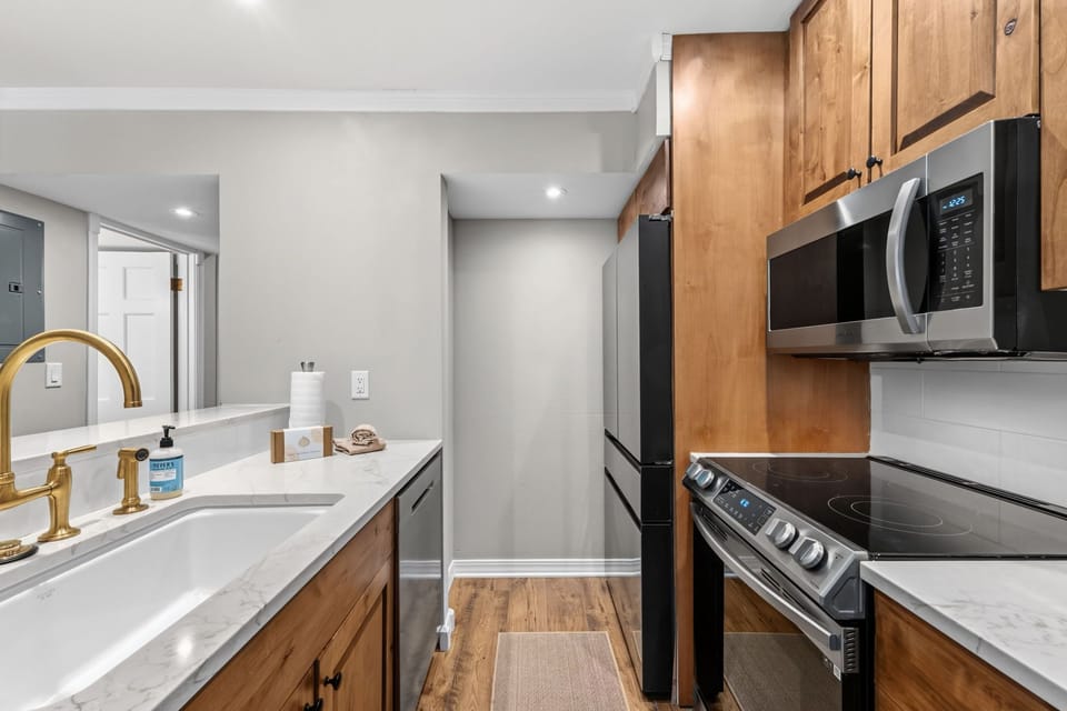 Step into your stylish kitchen with warm wood cabinetry, marble countertops, and modern stainless appliances ready for your culinary adventures during your stay.