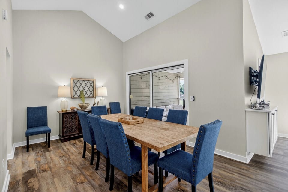 Gather around this spacious dining table with friends and family, where memories are made under soaring ceilings. The stylish blue chairs and natural wood create a warm, inviting atmosphere for your meals together.