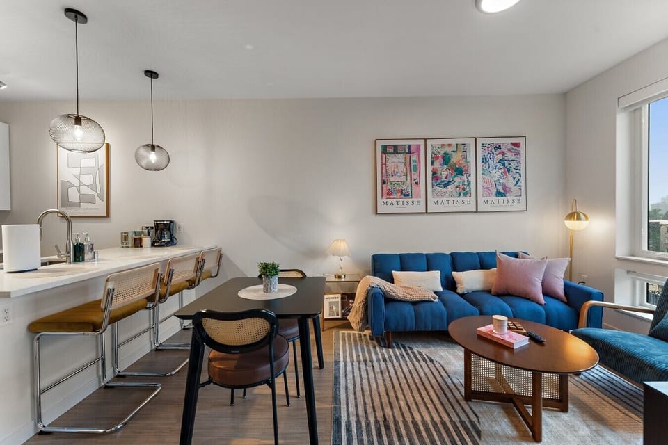 Open-concept living, dining, and kitchen area with comfortable seating, workspace, and natural light