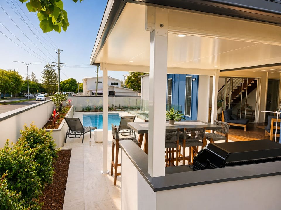 Covered poolside patio with grill, dining area, and seamless indoor-outdoor flow