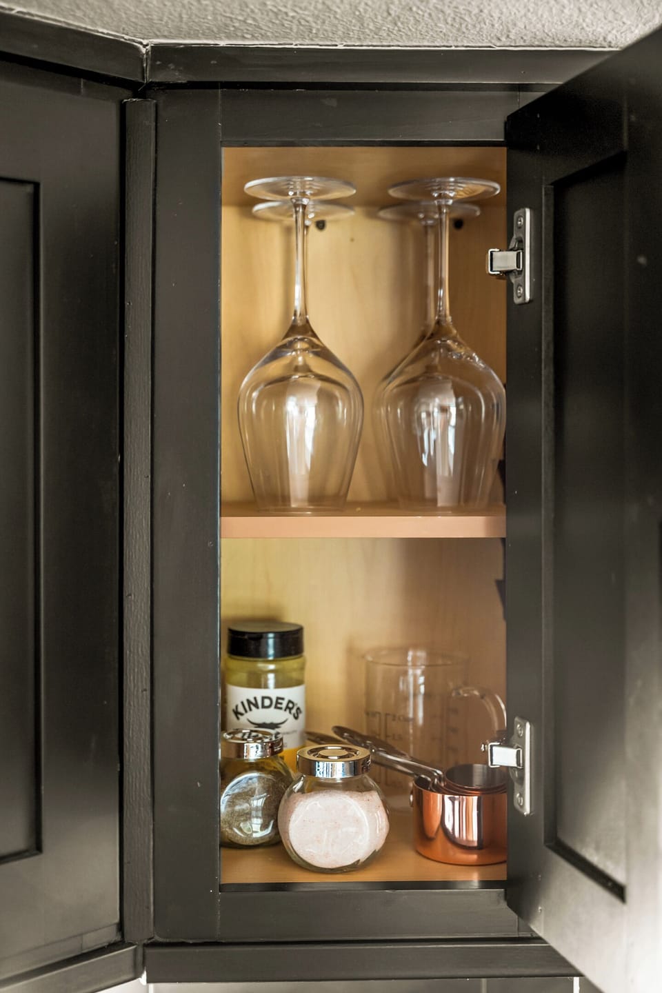Pull two glasses down and pour something from the rack — the cabinet's stocked for it.