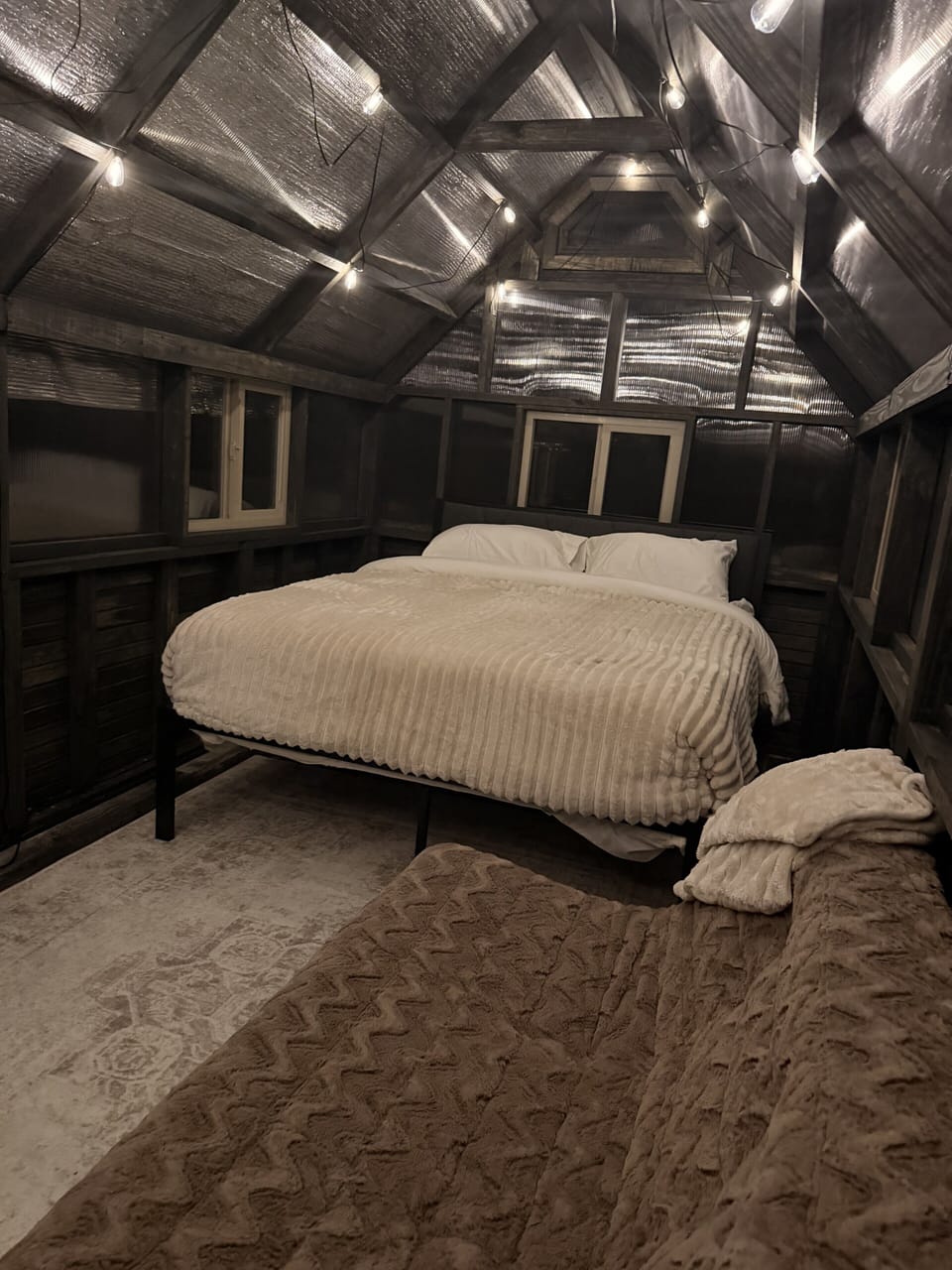 Cozy loft bedroom with warm lighting, rustic charm, and plush bedding