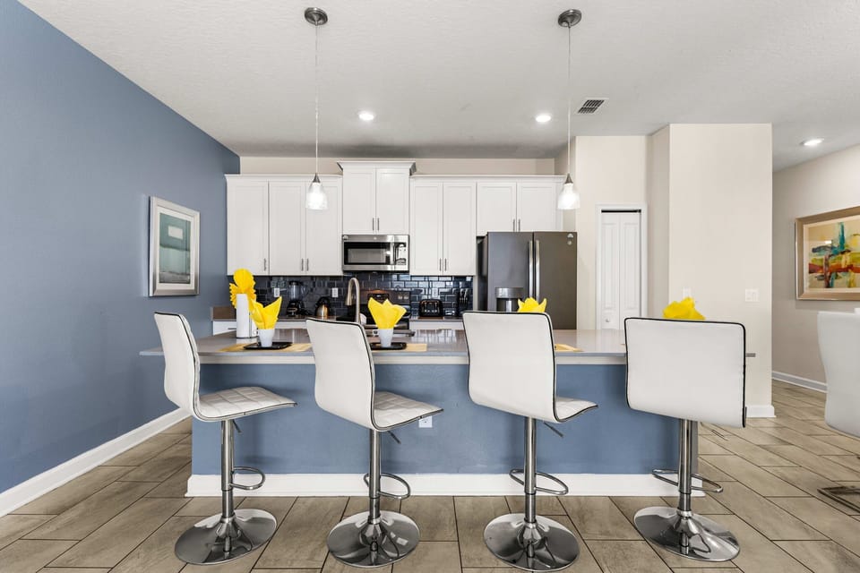 Bright and cheerful kitchen with a cozy breakfast bar, white cabinets, and stainless steel appliances. Ideal for preparing meals with a modern touch.