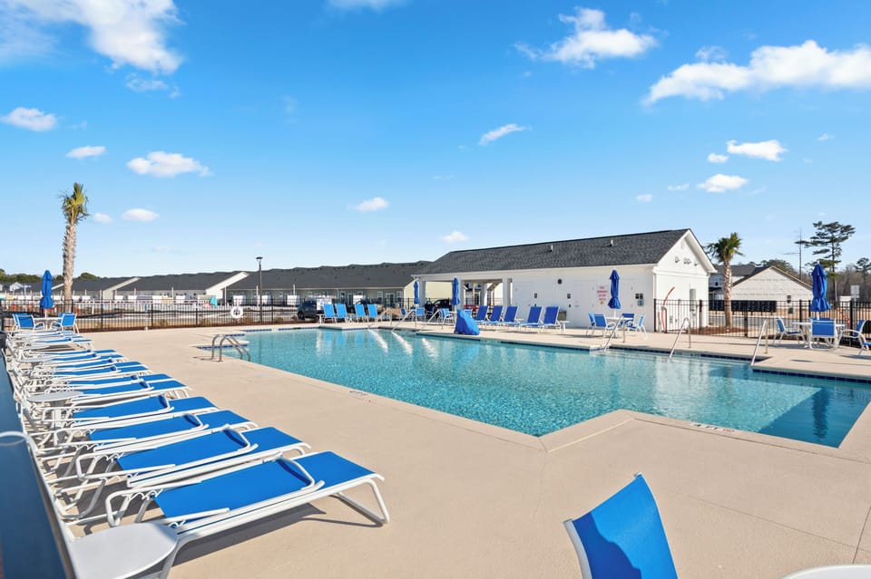 Expansive community swimming pool area featuring rows of comfortable blue lounge