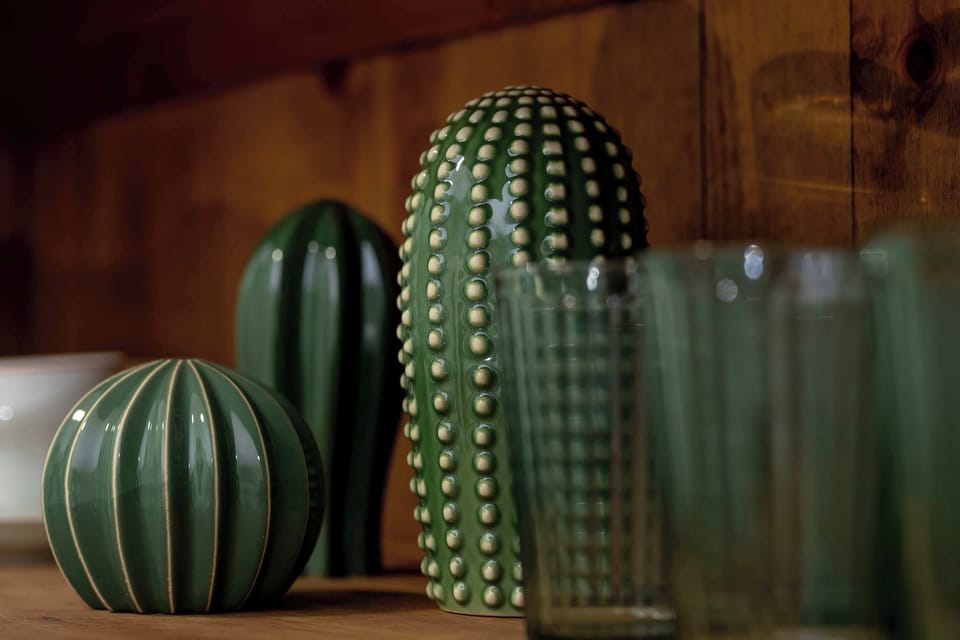 A collection of green glass bottles arranged decoratively on a shelf. Reflections and varying shapes create visual appeal.