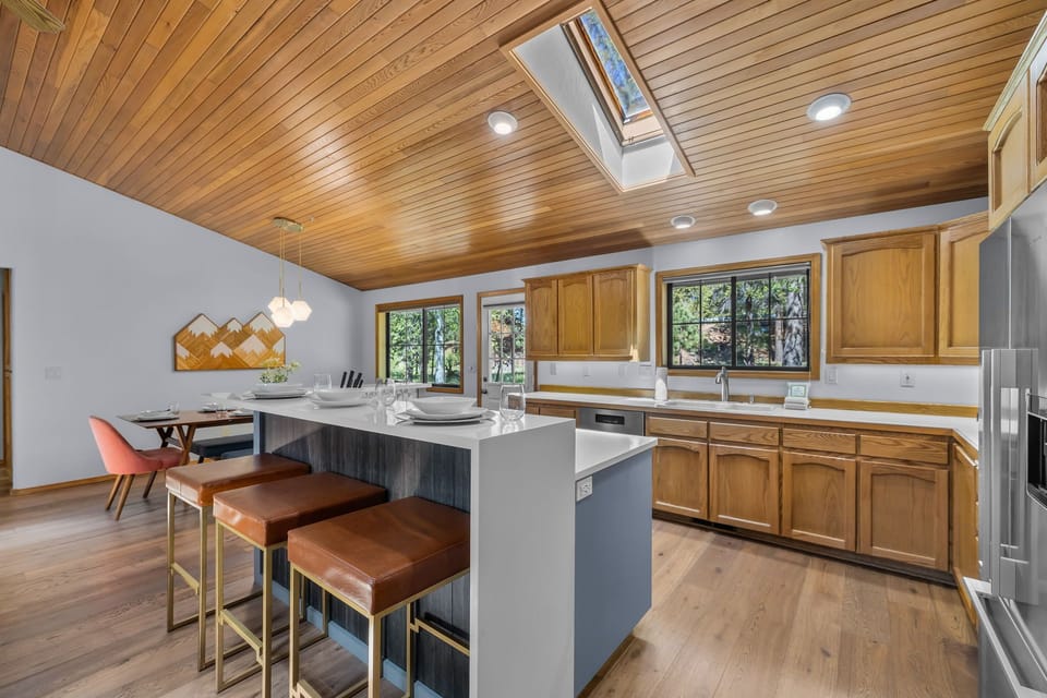 Gather around the spacious island for morning coffee or evening meals beneath a vaulted wood ceiling and skylight that floods the kitchen with natural light.