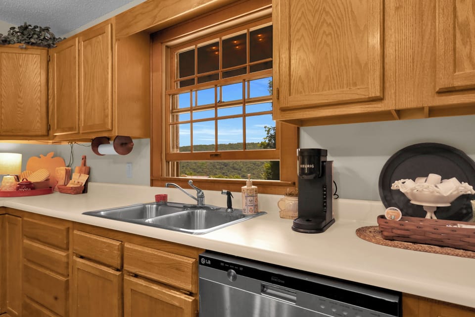 Cook up something delicious in this bright kitchen, featuring scenic window views, a coffee station, and warm wood finishes — the perfect gathering spot for mountain mornings.