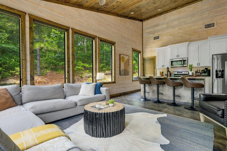 Bright open living space with forest views and modern kitchen seating