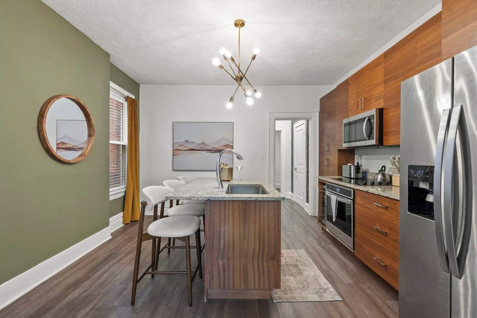 Sleek kitchen w/ stainless steel appliances, wood cabinetry & a chic island for casual dining.